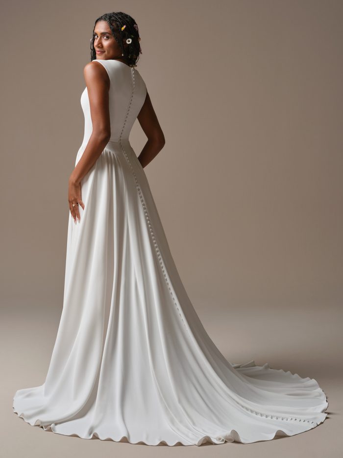 Minimalist A-line wedding dress with high neckline, button-back detail, and long train.
