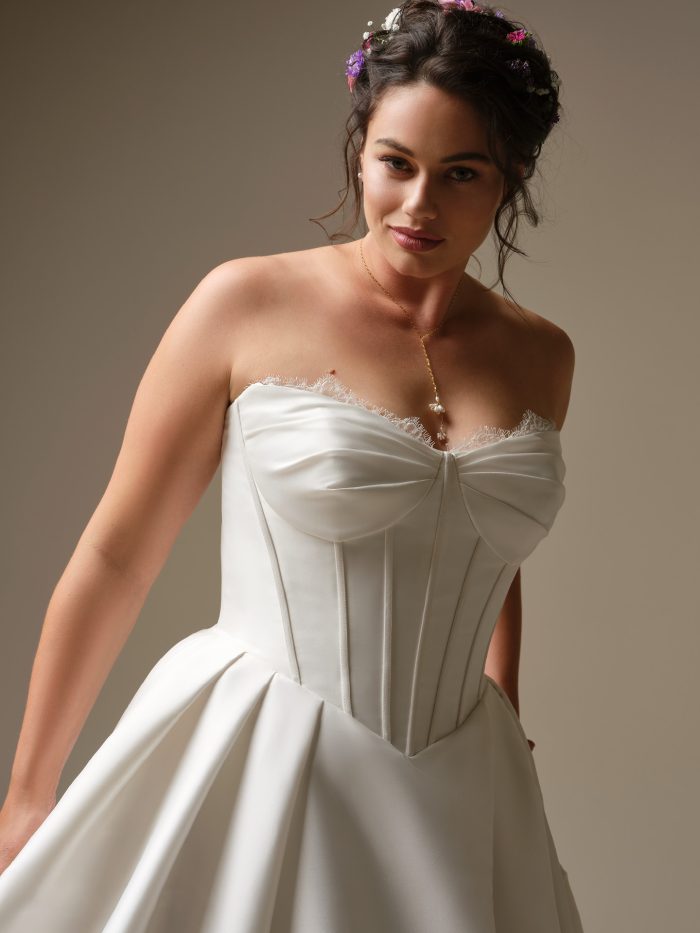 Close-up of Rebecca Ingram Zorina ballgown wedding dress with a strapless neckline, corset construction, and clean satin finish, highlighting a defined waist and elegant, structured fit.