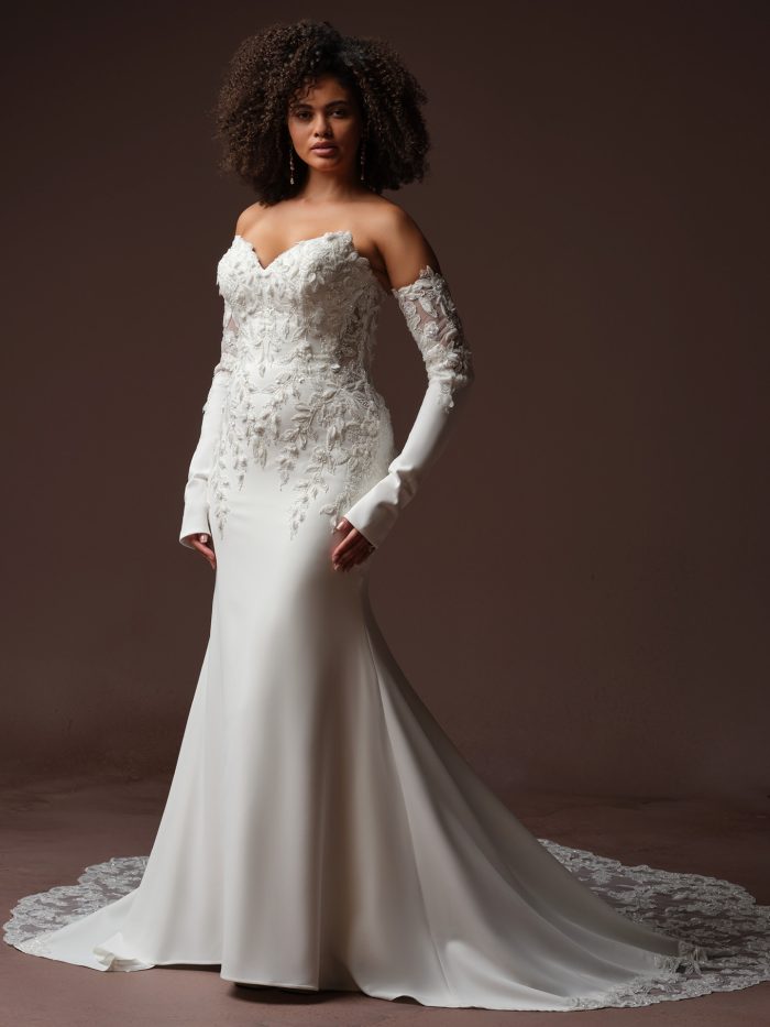 Blair sheath wedding dress by Sottero and Midgley featuring a strapless sweetheart neckline with lace appliqués and detachable long sleeves with sheer floral detailing, shown in a full-length front view.