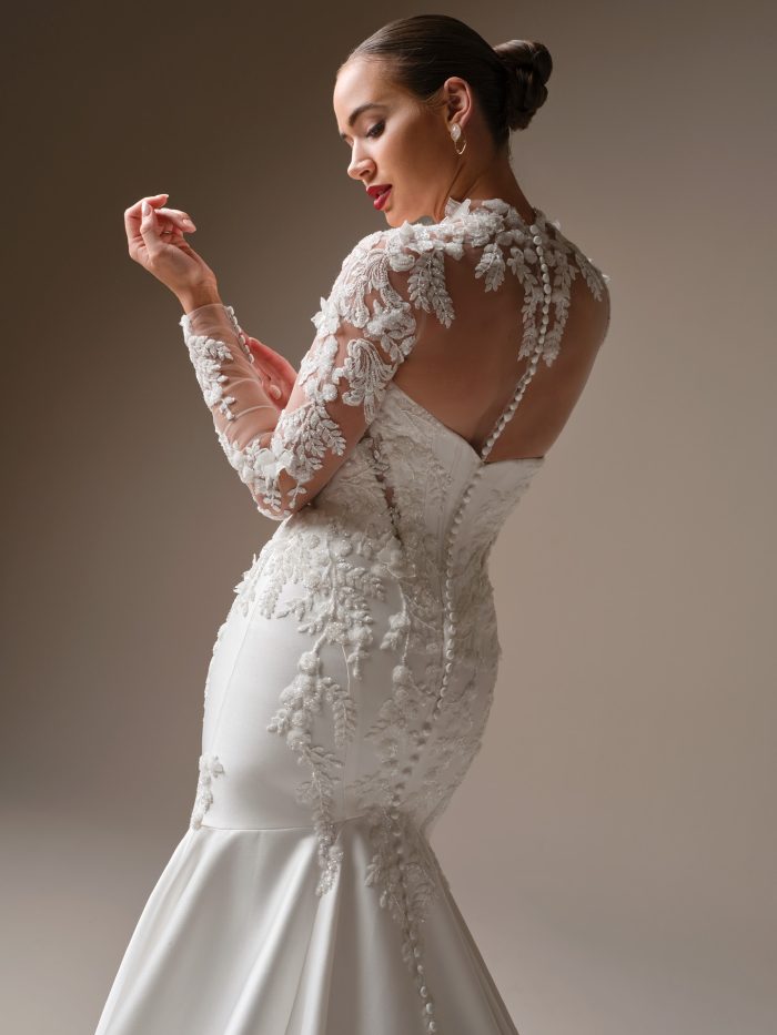 Back view of Burke by Sottero and Midgley fit-and-flare wedding dress featuring beaded 3-D lace motifs, illusion lace sleeves, and covered buttons down the back.