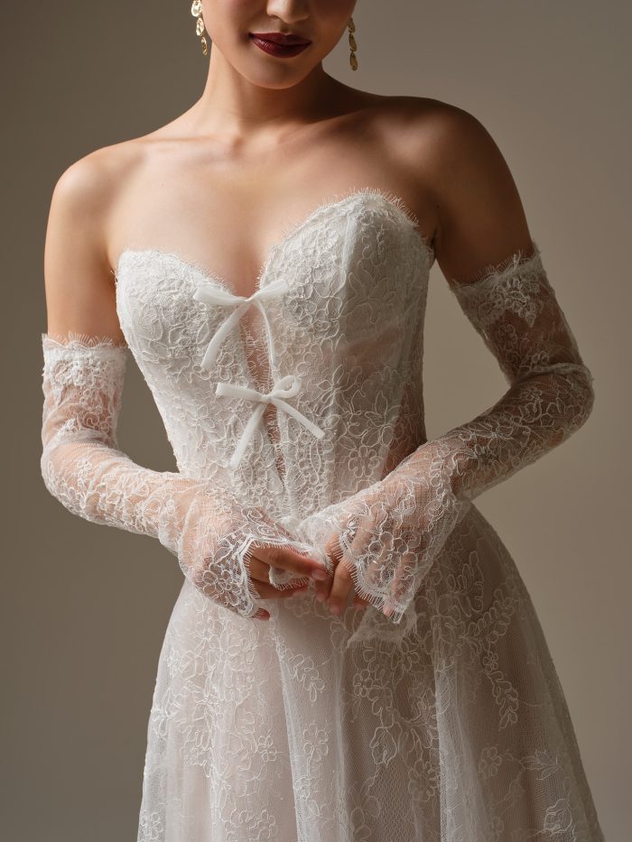 Close-up of Granger by Sottero and Midgley wedding dress featuring Chantilly lace, illusion bodice with exposed boning, and delicate bow detail at the sweetheart neckline.