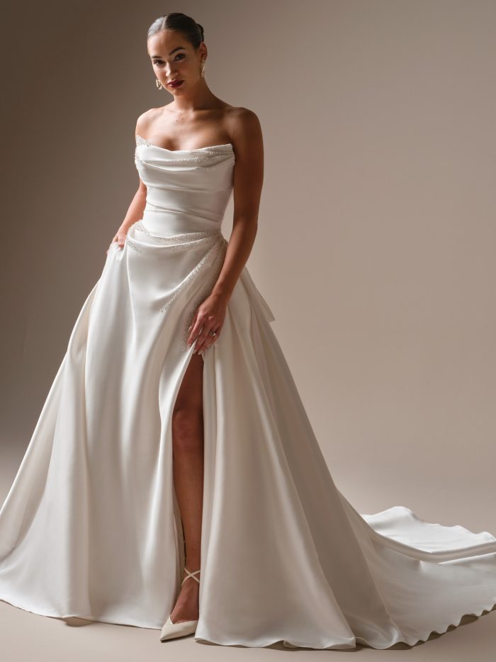 Strapless satin ball gown wedding dress with draped neckline, high slit, and full skirt.
