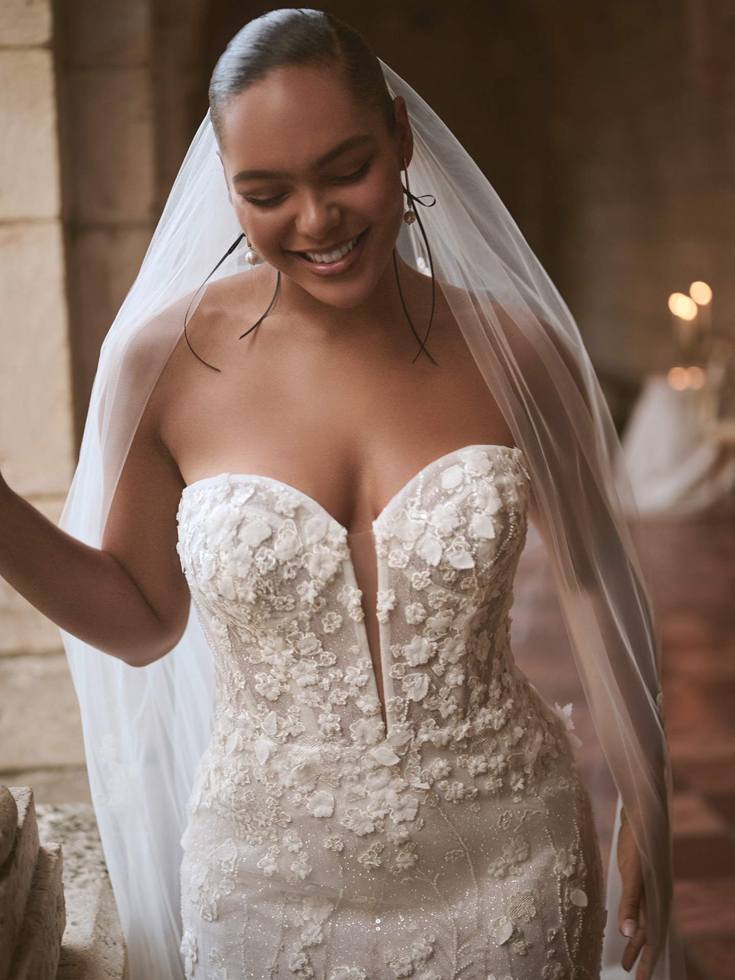 Close-up of Sottero and Midgley Noor sheath wedding dress with a structured strapless bodice, delicate floral appliqué, and subtle shimmer, highlighting a sculpted, curve-enhancing fit with romantic detail.