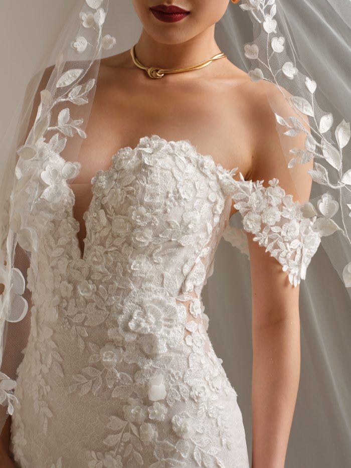 Close-up of Rashida by Sottero and Midgley fit-and-flare wedding dress featuring beaded lace appliqués, floral details, and illusion neckline with lace sleeves.