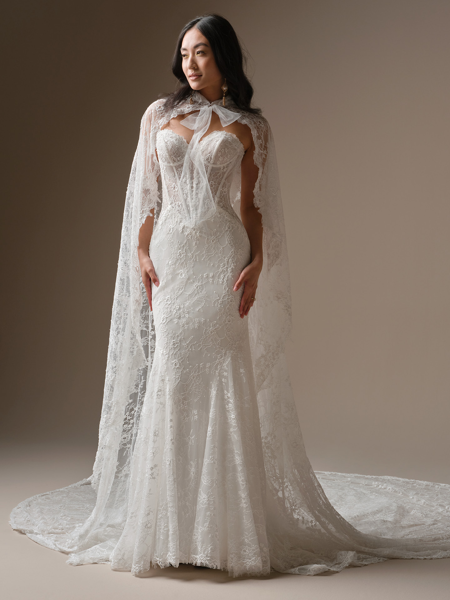 Bellevue by Maggie Sottero fit-and-flare lace wedding dress with strapless sweetheart neckline and detachable sheer lace cape sleeves with bow detail