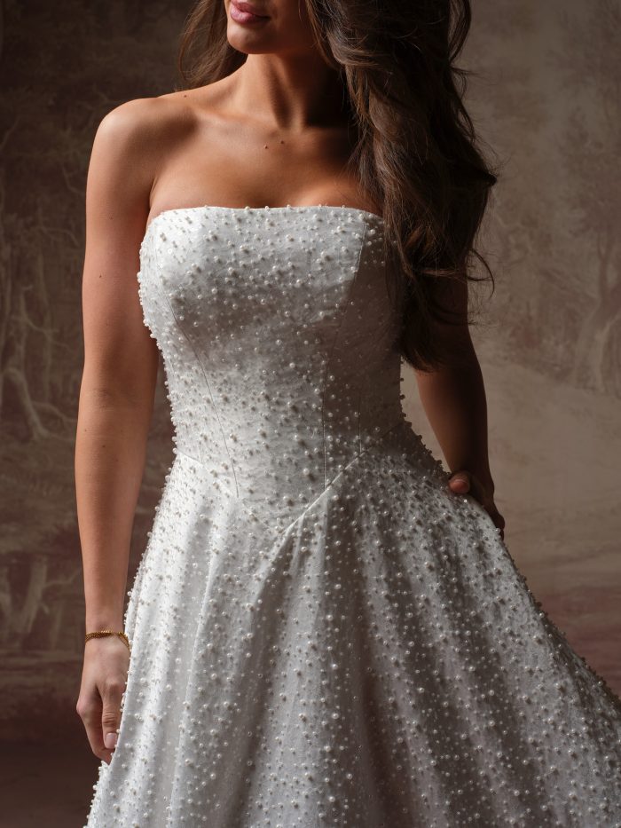 Maggie Sottero Elowyn A-line wedding dress, close-up detail — strapless pearl-beaded bodice and A-line skirt with allover pearl scatter.