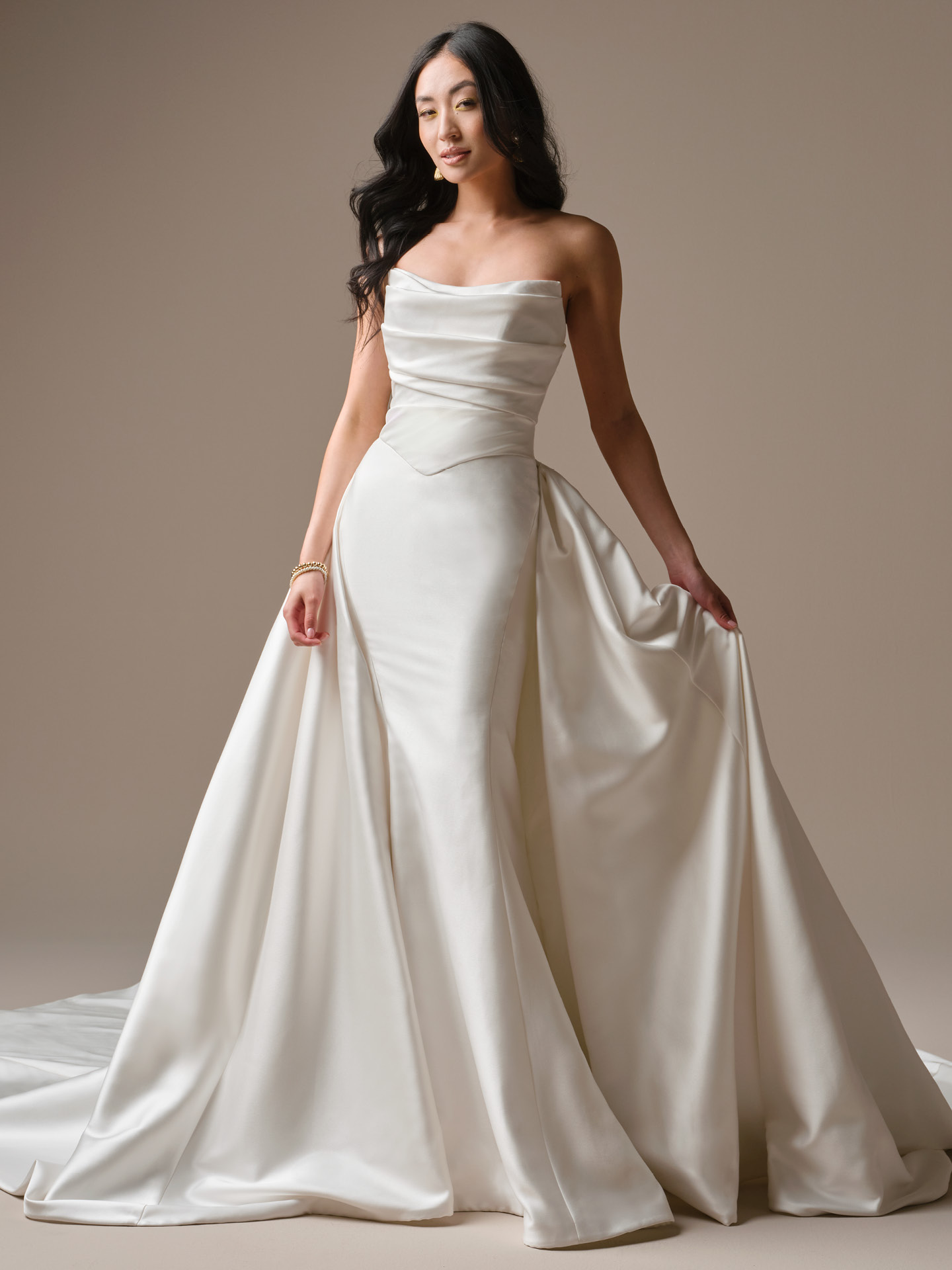Maureen Lane by Maggie Sottero fit-and-flare satin wedding dress with softly draped strapless neckline, sculpted bodice, and dramatic side overskirt detail