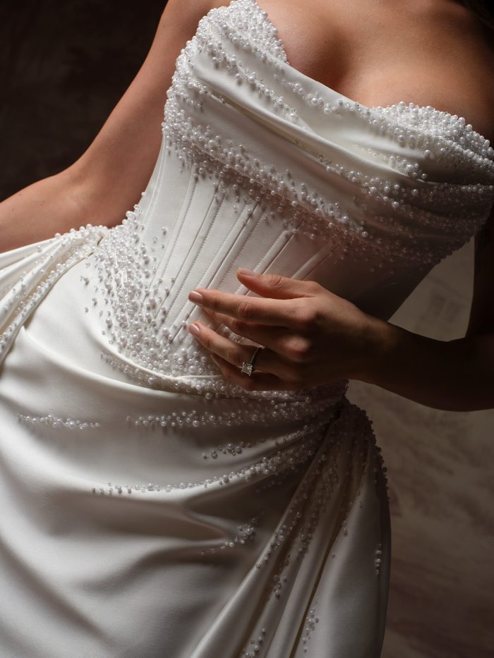 Maggie Sottero Melissa Royale fit-and-flare wedding dress, close-up detail — pearl-beaded satin corset bodice with draped ruching.