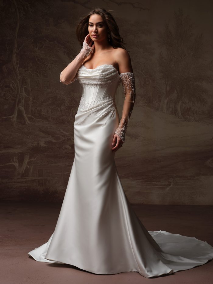 Maggie Sottero Melissa Royale wedding dress with sleeves, front view on model — pearl-beaded off-the-shoulder bodice with sheer beaded sleeves and fitted satin mermaid skirt with train.