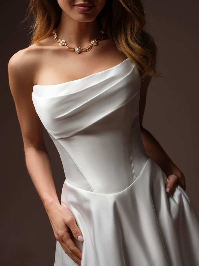 Maggie Sottero Morganna Marie A-line wedding dress, close-up detail — draped asymmetrical satin bodice with fitted seaming.