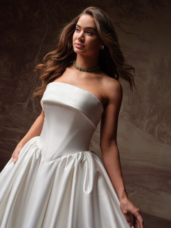 Maggie Sottero Rane ballgown wedding dress, close-up detail — sleek strapless satin bodice with structured seaming and gathered full skirt.