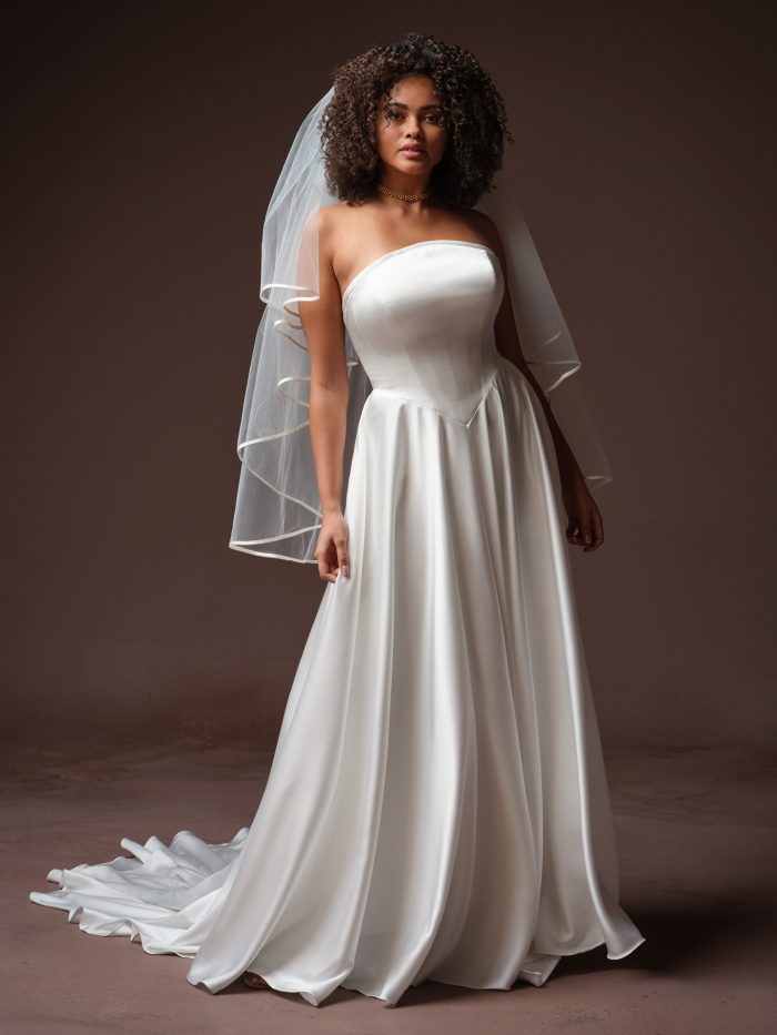 Maggie Sottero Tiffany A-line wedding dress, front view on model — strapless satin bodice with flowing A-line skirt and dramatic train, shown with tiered veil.