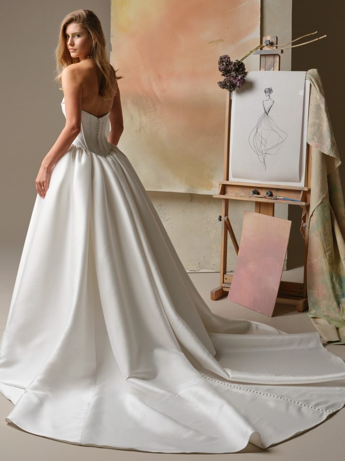 Back view of Yuma ball gown wedding dress with corset bodice, covered button detail, and extended satin train