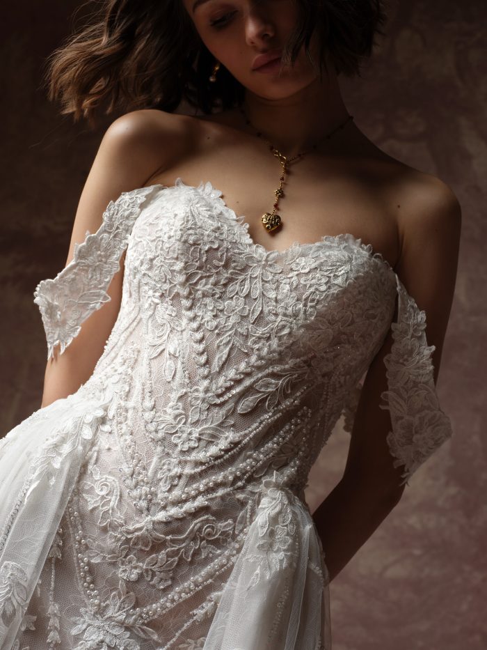 Sottero and Midgley Hester wedding dress with cap sleeves, close-up detail — beaded floral lace bodice with pearl trim and off-the-shoulder lace sleeves.