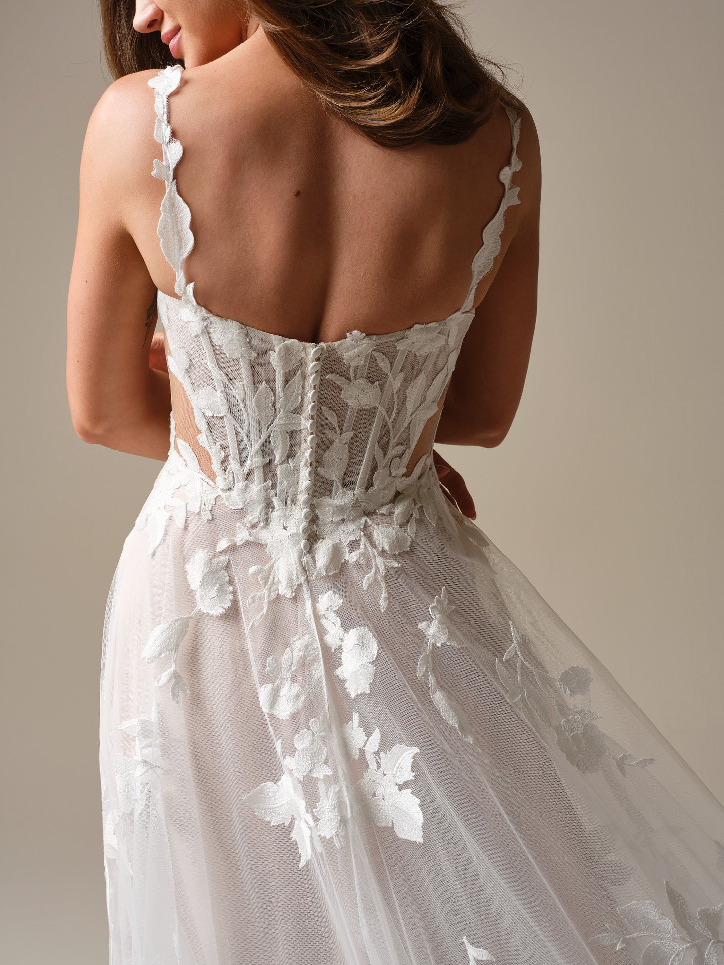 Maggie Sottero Natalie Marie wedding dress close-up showcasing sheer illusion bodice detailing, dimensional floral motifs, and a button-back finish for a feminine, modern touch
