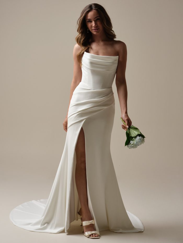 Rebecca Ingram Kailani strapless crepe goddess wedding dress with cowl neckline, asymmetric draped skirt, thigh-high slit and sweep train