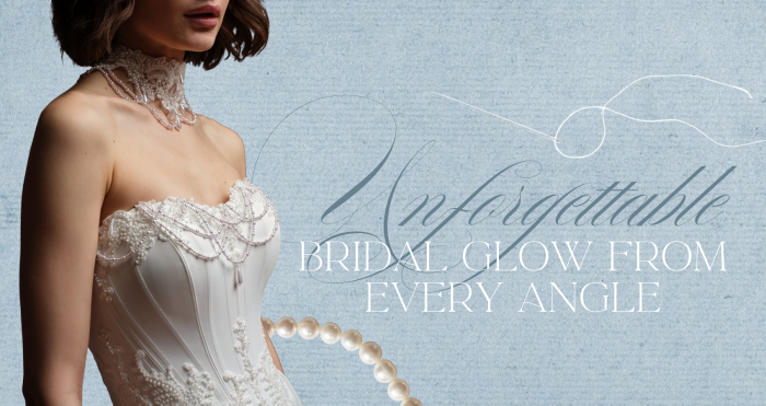 Maggie Sottero Seattle wedding dress, with text reading 'Unforgettable Bridal Glow From Every Angle.' Close-up of the gown's strapless sweetheart corset bodice with pearl swag beading, scalloped lace trim, and lace appliqués at the waist, styled with a lace and pearl choker. A strand of oversized pearls is layered over the dusty blue textured background.
