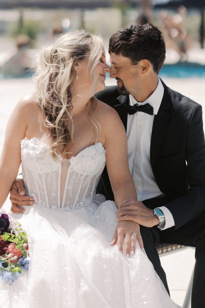 Athlone wedding dress by Sottero and Midgley in a close-up view, highlighting the strapless floral-appliqué bodice with sheer corsetry and delicate beading. The gown is styled in a romantic moment with a partner, emphasizing the intricate detailing and soft tulle skirt.