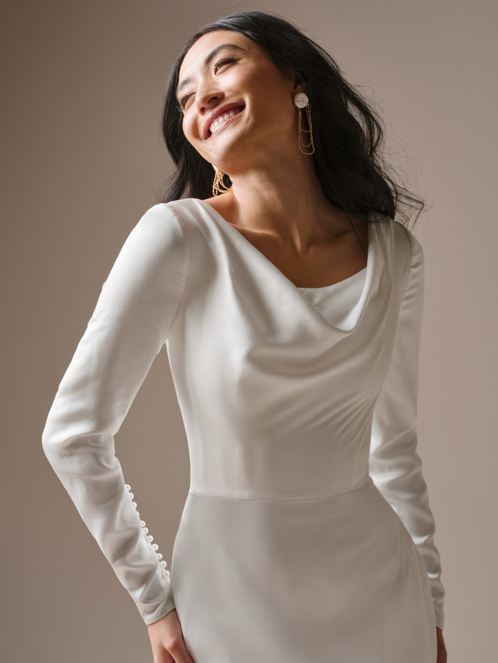 Close-up of the Maggie Sottero Melinda's draped cowl neckline and smooth satin long sleeves, finishing at the wrist with a delicate row of pearl buttons.