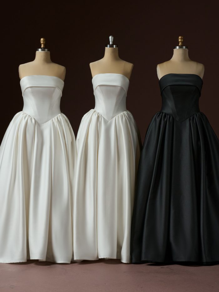Rane ballgown wedding dress by Maggie Sottero displayed on three dress forms, shown in ivory, soft white, and black colorways. The strapless design features a clean folded neckline, structured corset bodice with vertical seaming, and a full gathered skirt that falls into soft volume.