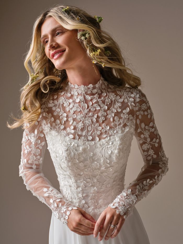 Georgina jacket accessory by Rebecca Ingram in a front view, showcasing the illusion high neckline, long sheer sleeves, and intricate allover floral appliqués layered over a structured bodice.