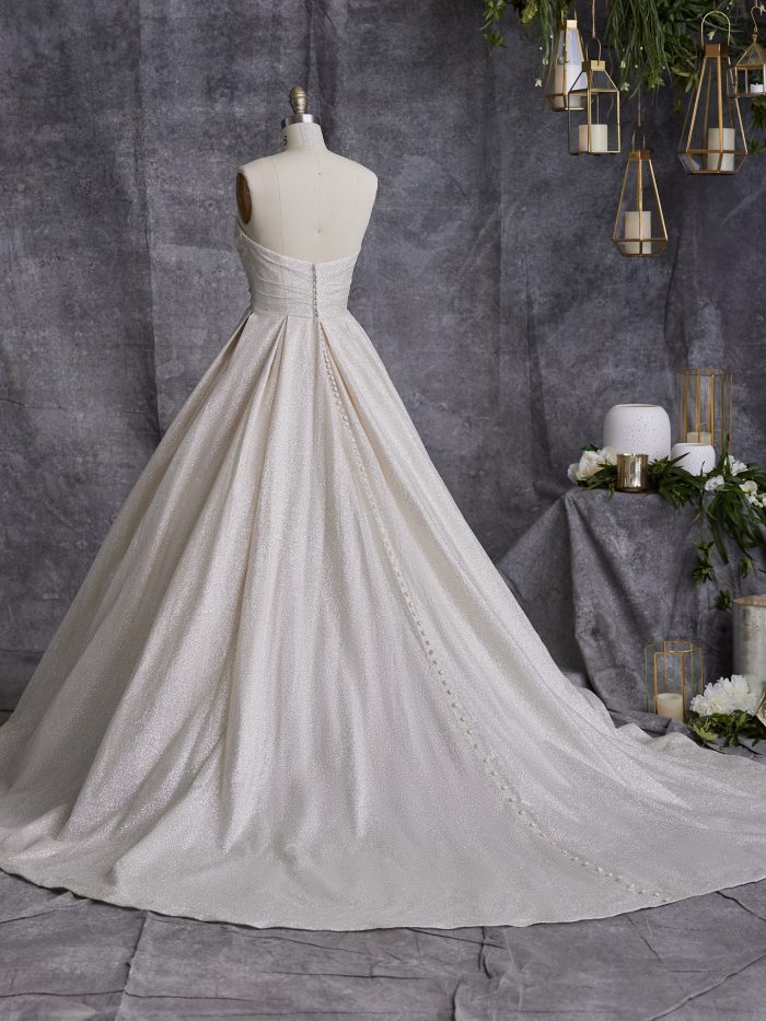 Back view of the Anniston ball gown wedding dress by Maggie Sottero on a dress form, showing a strapless sweetheart back with covered button closure down the full shimmer tulle ball gown skirt and train.