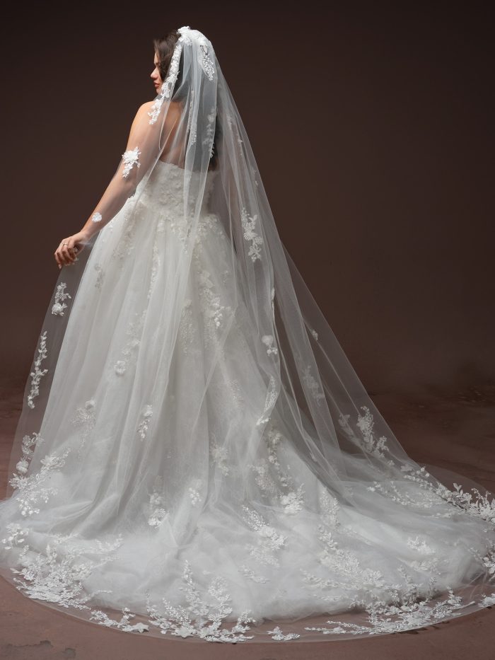 Maggie Sottero Benton ballgown wedding dress in ivory, curve fit — back view showing strapless lace bodice and full tulle ballgown skirt with 3D floral appliqués, styled with a cathedral-length matching lace veil.