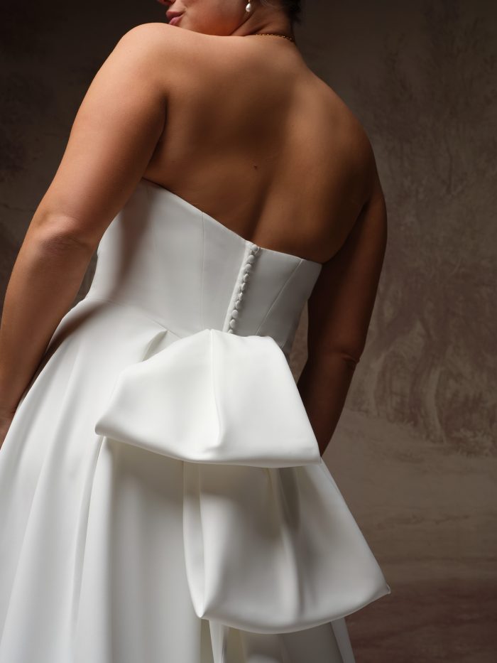 Close-up back view of the Calliope gown by Maggie Sottero, showing the strapless bodice with covered buttons and oversized satin bow detail.