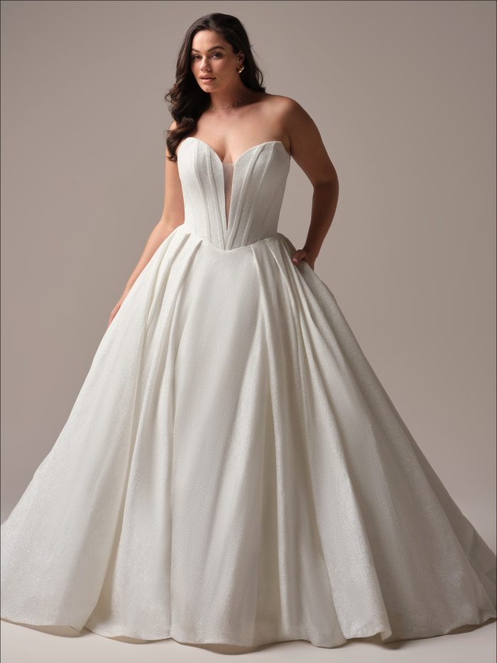 Front view of the Derrick Royale ball gown wedding dress by Maggie Sottero in curve fit, featuring a deep plunging strapless neckline with structured seaming and a full shimmer ball gown skirt with train.