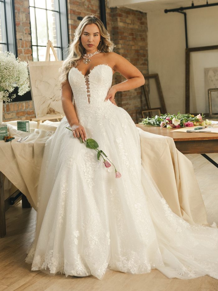 Maggie Sottero Jennifer ballgown wedding dress in ivory, curve fit — strapless plunging lace bodice with sheer illusion insert, full sparkling tulle ballgown skirt with lace appliqués and train, styled with a pearl choker.