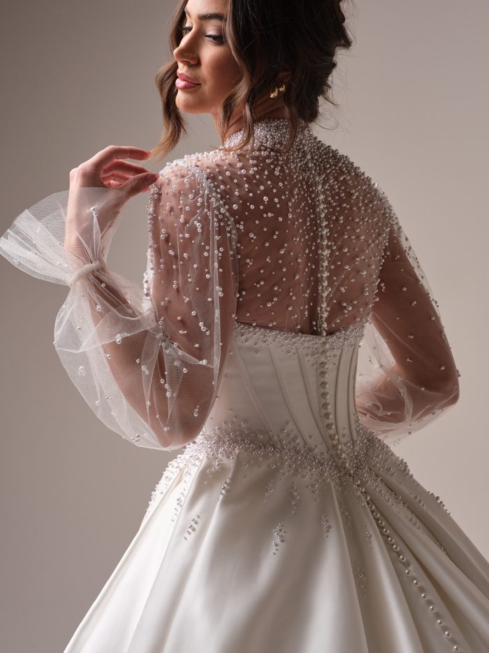 Back view of the Juneau gown by Maggie Sottero, highlighting the pearl-beaded sheer back, corset bodice, and full satin ball skirt.