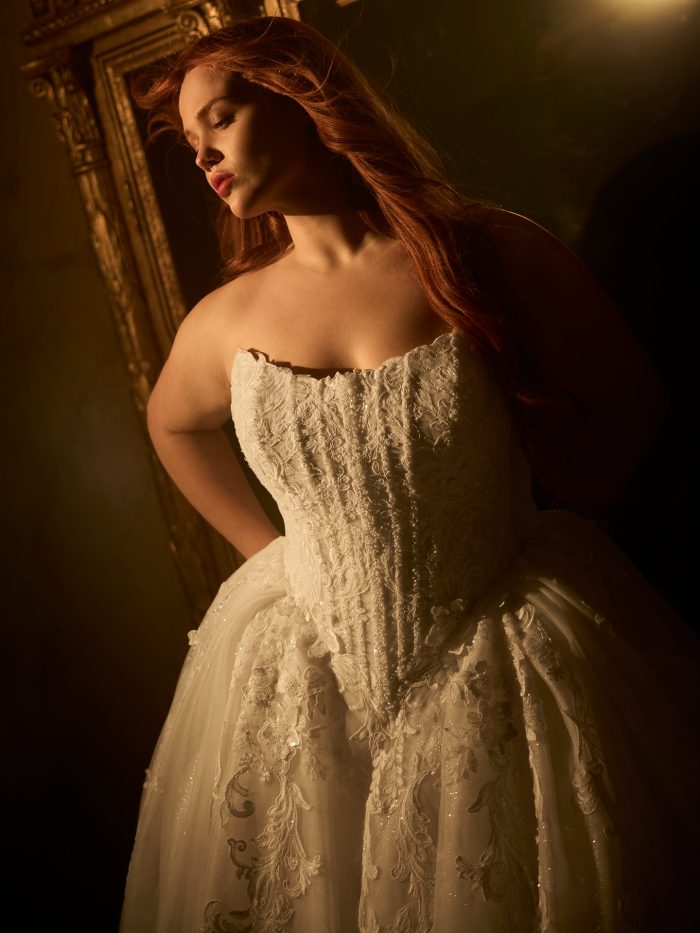 Maggie Sottero Lyra ballgown wedding dress in ivory, curve fit — close-up of the strapless beaded lace corset bodice with sparkling embellishment against a gilded interior setting.