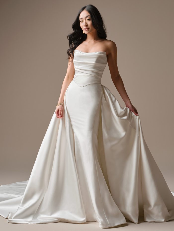 Maggie Sottero Maureen Train Accessory in white, shown styled over the Maureen fit and flare dress, featuring a strapless draped cowl neckline with ruched satin bodice and a detachable voluminous smooth satin overskirt with cathedral train.