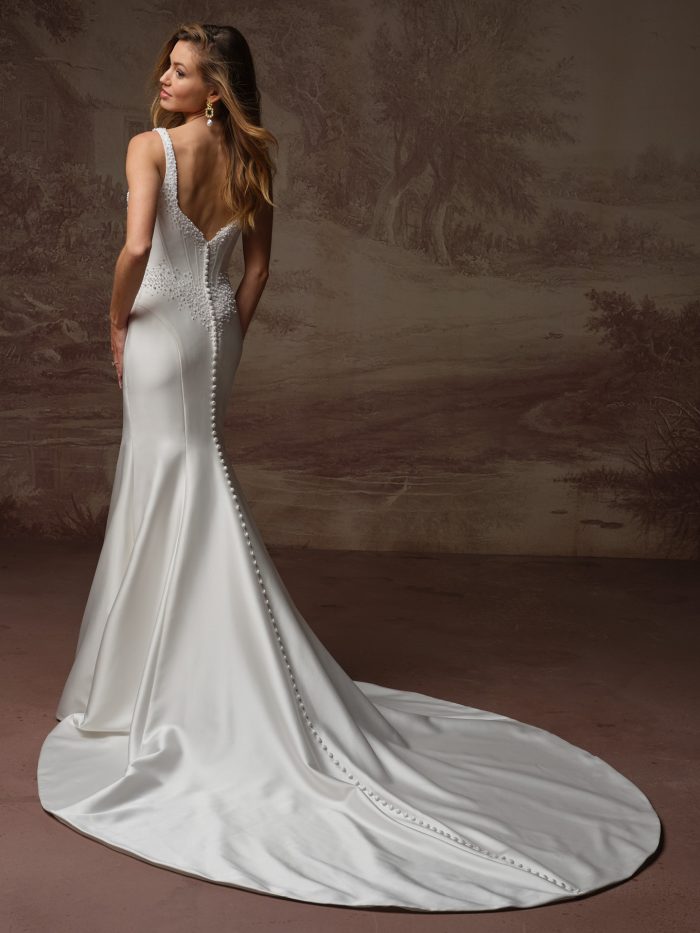 Back view of the Melissa Marie Royale wedding dress by Maggie Sottero, showing a low V-back with pearl beading, corset button closure down the fitted satin skirt, and long train.