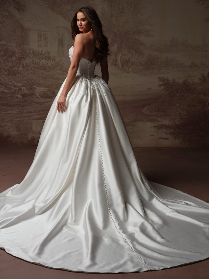 Back view of the Melissa Royale gown by Maggie Sottero, showing the corset back with covered buttons and a full satin ball gown skirt.