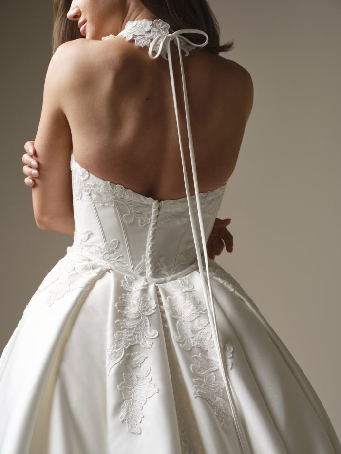 Back view of the Serafina Lane gown by Maggie Sottero, showing the lace corset back, covered buttons, and a ribbon-tied lace choker.