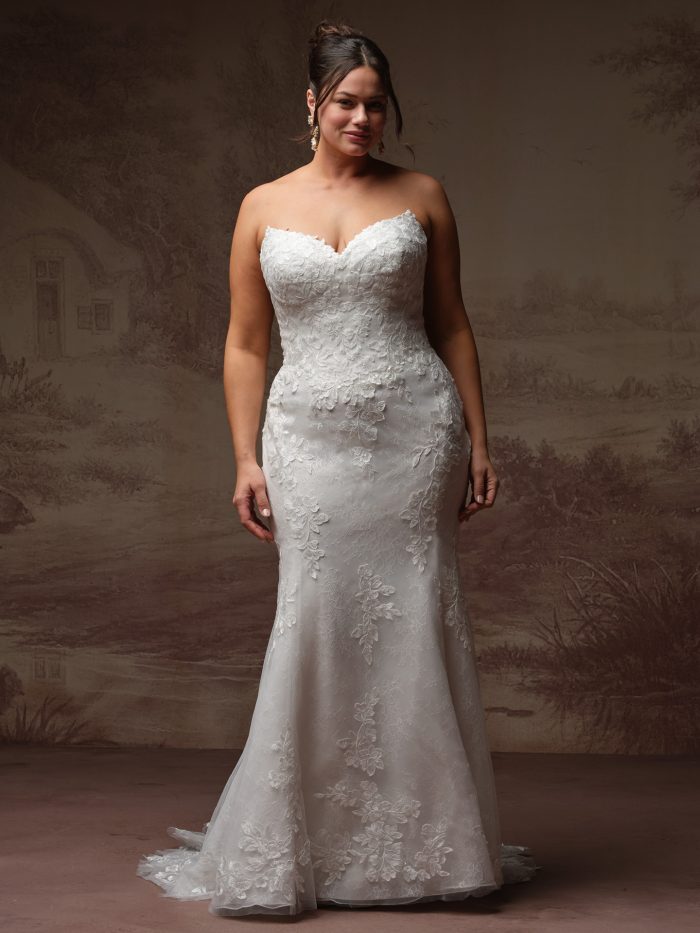 Rebecca Ingram Brandy fit-and-flare wedding dress in ivory, curve fit — strapless sweetheart neckline with floral lace appliqués over a fitted mermaid silhouette with lace-edged train.