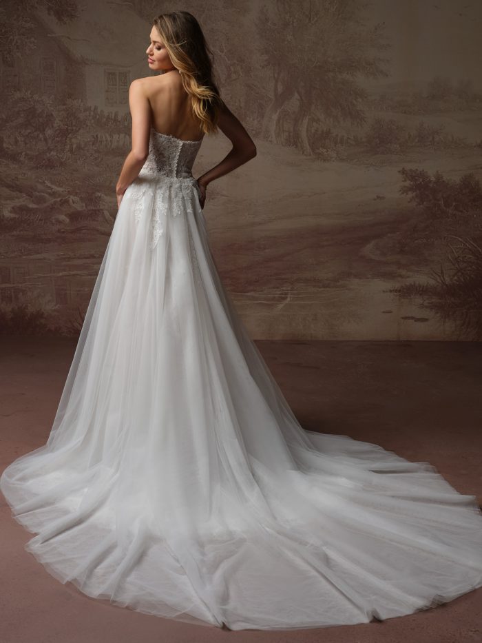 Back view of the Esmeralda Lane gown by Rebecca Ingram, showing the strapless corset back and flowing tulle overskirt train.
