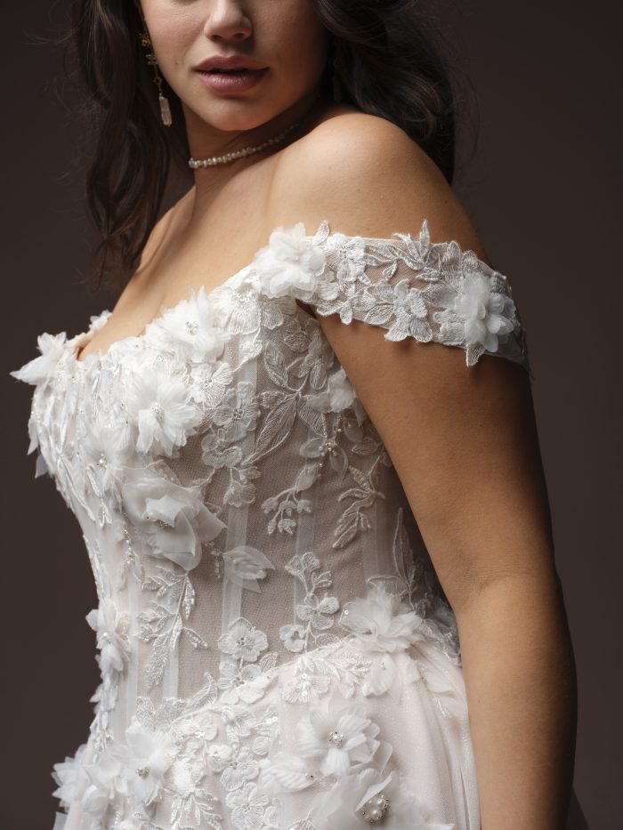 Rebecca Ingram Fleur ballgown wedding dress in ivory, curve fit — close-up of the off-the-shoulder lace sleeve and bodice with 3D floral appliqués and beaded detailing.