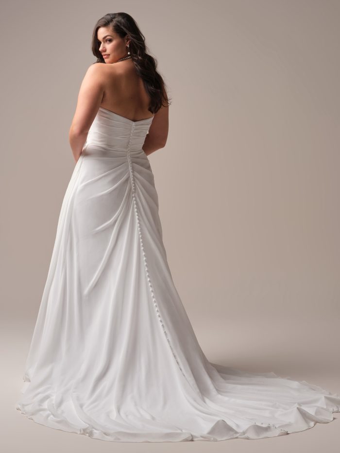 Rebecca Ingram Francesca A-line wedding dress in diamond white, curve fit — back view showing strapless ruched bodice with covered button closure down the length of the fitted chiffon skirt and train.