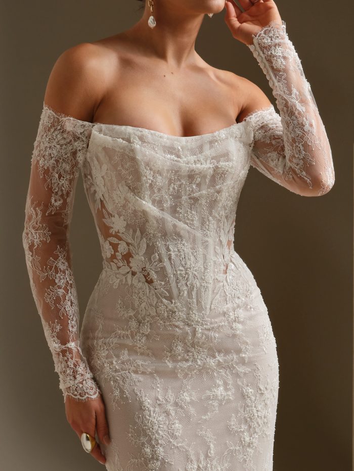 Close-up of the Dublin gown by Sottero and Midgley, showing the draped off-shoulder bodice and detailed floral lace sleeve.