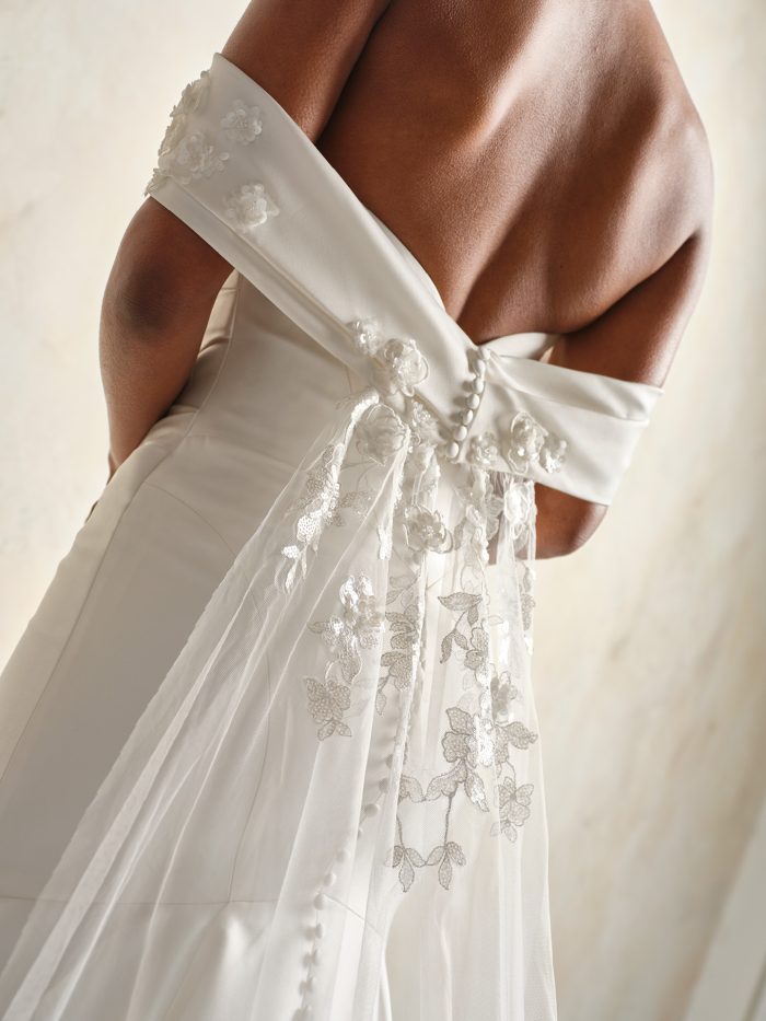 Close-up back view of the Giselle gown by Sottero and Midgley, showing the off-shoulder draped detail, covered buttons, and a floral lace-trimmed veil tied at the back.