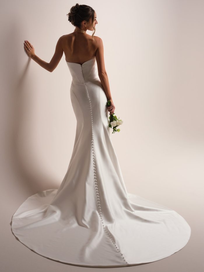 Back view of the Giselle Lane wedding dress by Sottero and Midgley, showing a strapless sweetheart back with covered button closure down the fitted sheath skirt and train.