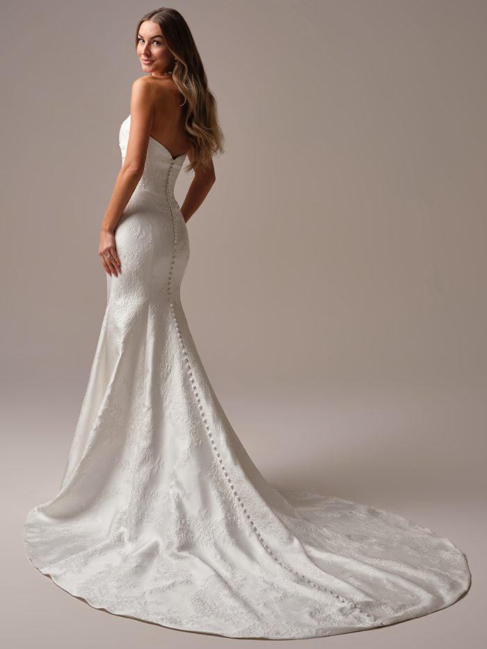 Back view of the Giselle Marie Lane wedding dress by Sottero and Midgley, showing a strapless sweetheart back with covered button closure down the fitted floral jacquard mermaid skirt and train.