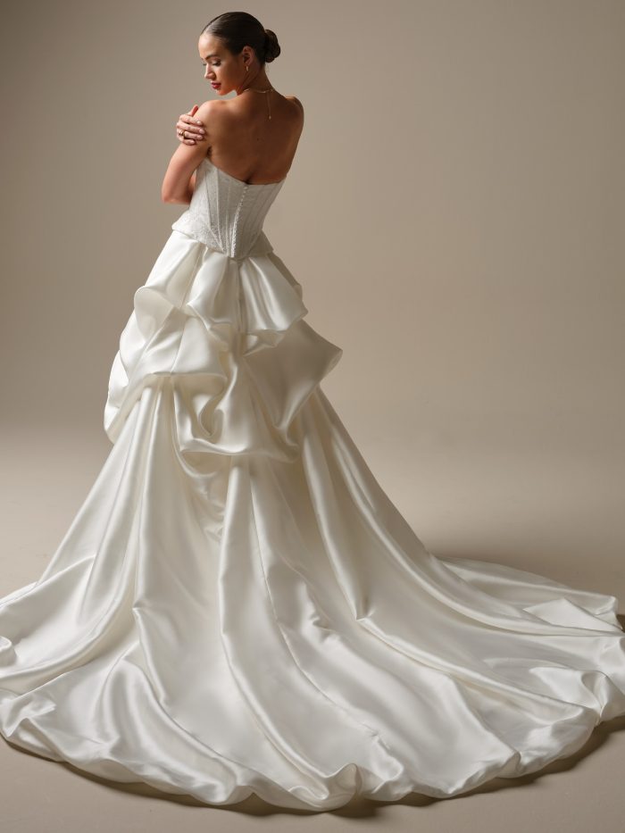 Back view of the Lassen Marie gown by Sottero and Midgley, showing the strapless corset back and dramatic gathered satin skirt with a full train.