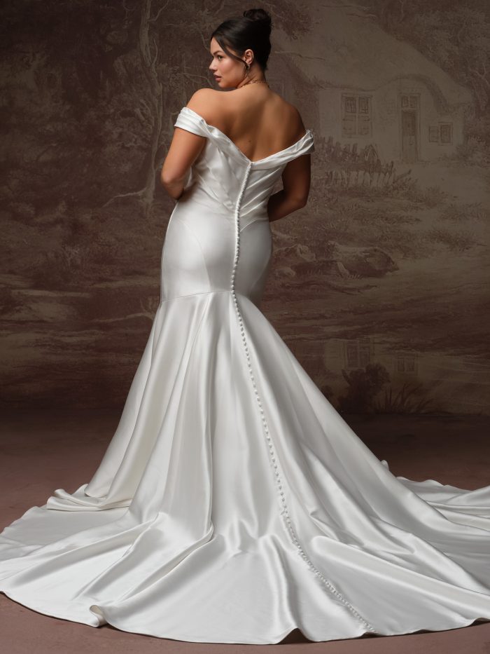 Sottero and Midgley Recine fit-and-flare wedding dress in ivory, curve fit — back view showing off-the-shoulder satin bodice with covered button closure and fitted mermaid skirt with dramatic train.