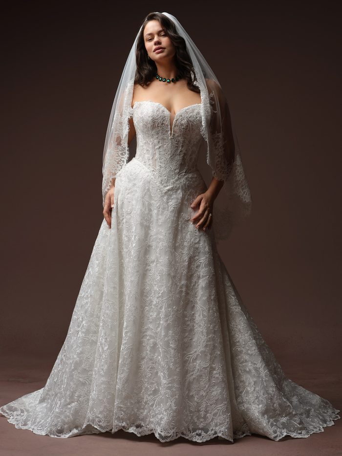 Front view of a curve model wearing the Amante Essentials Edit fingertip veil by Maggie Sottero in ivory with a lace-trimmed edge, paired with a strapless lace A-line wedding dress featuring a plunging sweetheart neckline.