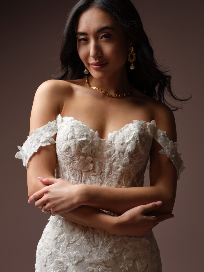 Close-up of the Estelle wedding dress by Maggie Sottero, showing the beaded floral lace bodice and off-the-shoulder cap sleeve detail.