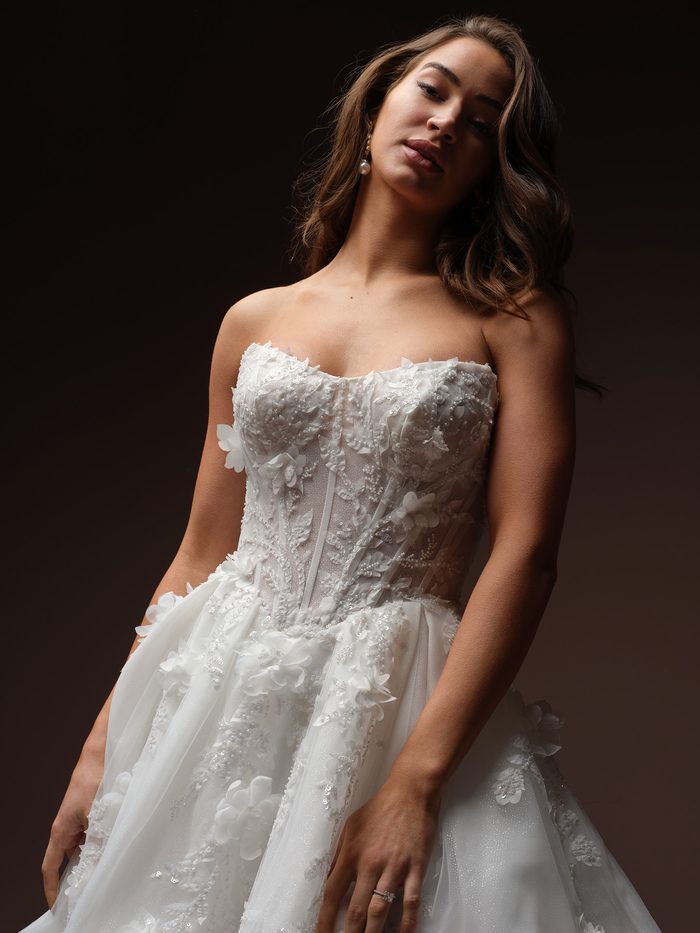 Close-up of the Fern A-line wedding dress by Maggie Sottero, showing the strapless sheer corset bodice with beaded vine embroidery and 3D floral appliqués.
