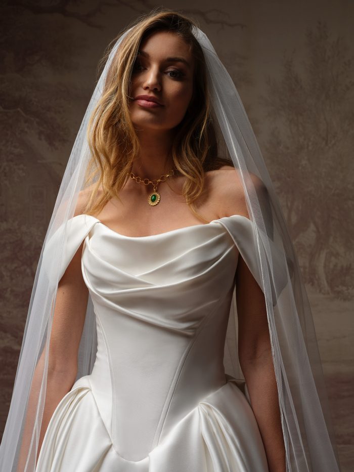 Close-up of the Fiorita wedding dress by Maggie Sottero, showing the draped satin off-the-shoulder bodice and cathedral veil.